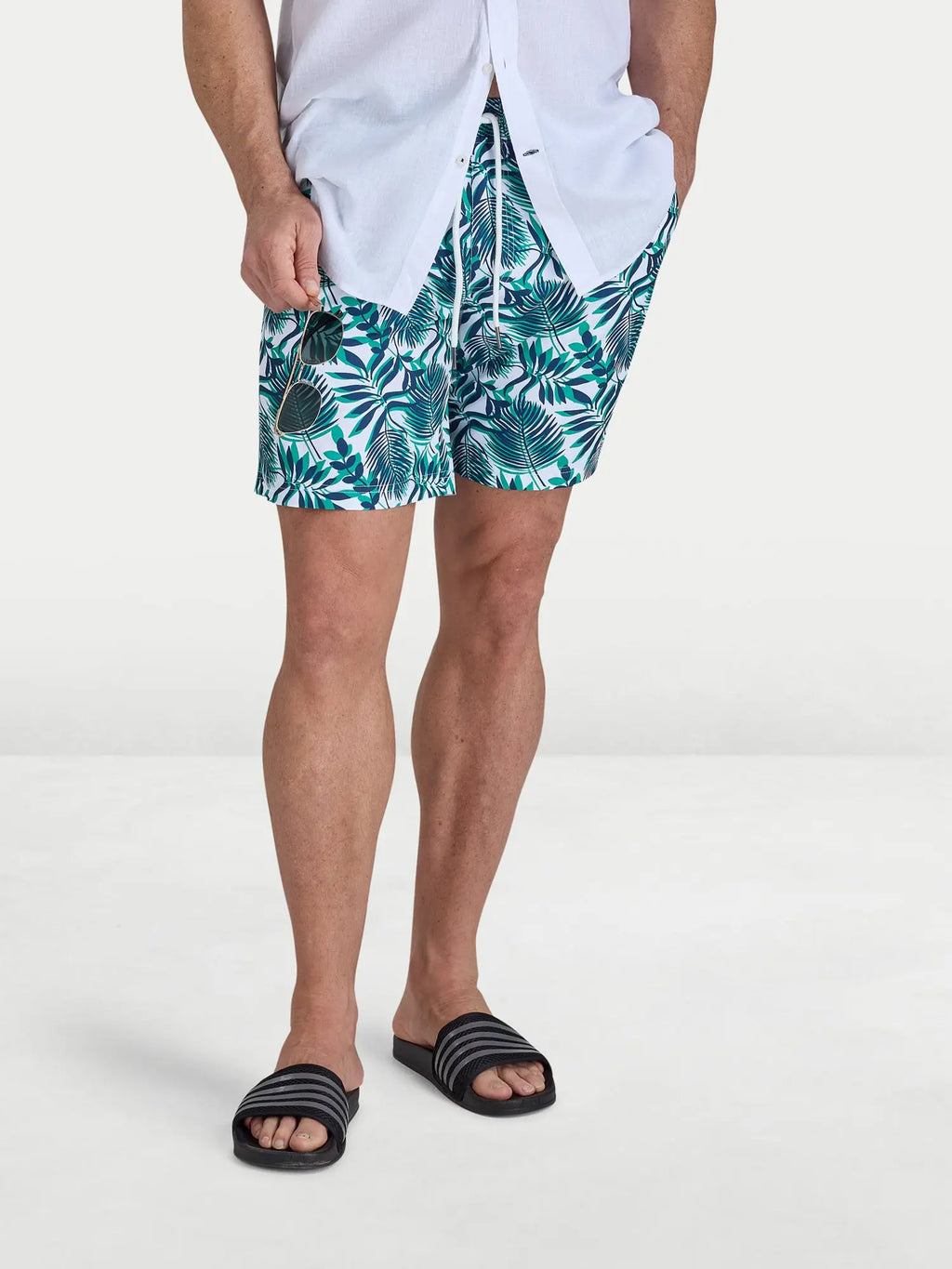 Man wearing Raging Bull Hawaiian Patterned Swim Shorts - Green and classic linen shirt in white, front detail. 