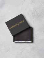 Brown leather wallet with 'Raging Bull' branding on a gray surface
