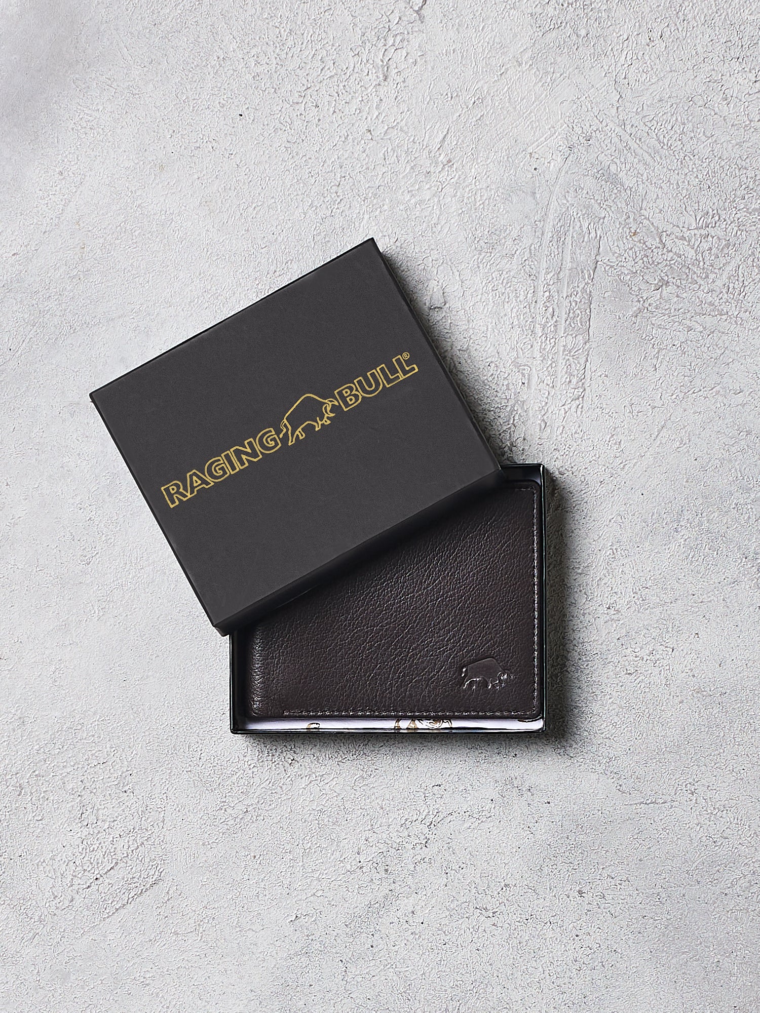 Brown leather wallet with 'Raging Bull' branding on a gray surface