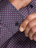 Close-up of a patterned shirt with a button being adjusted.