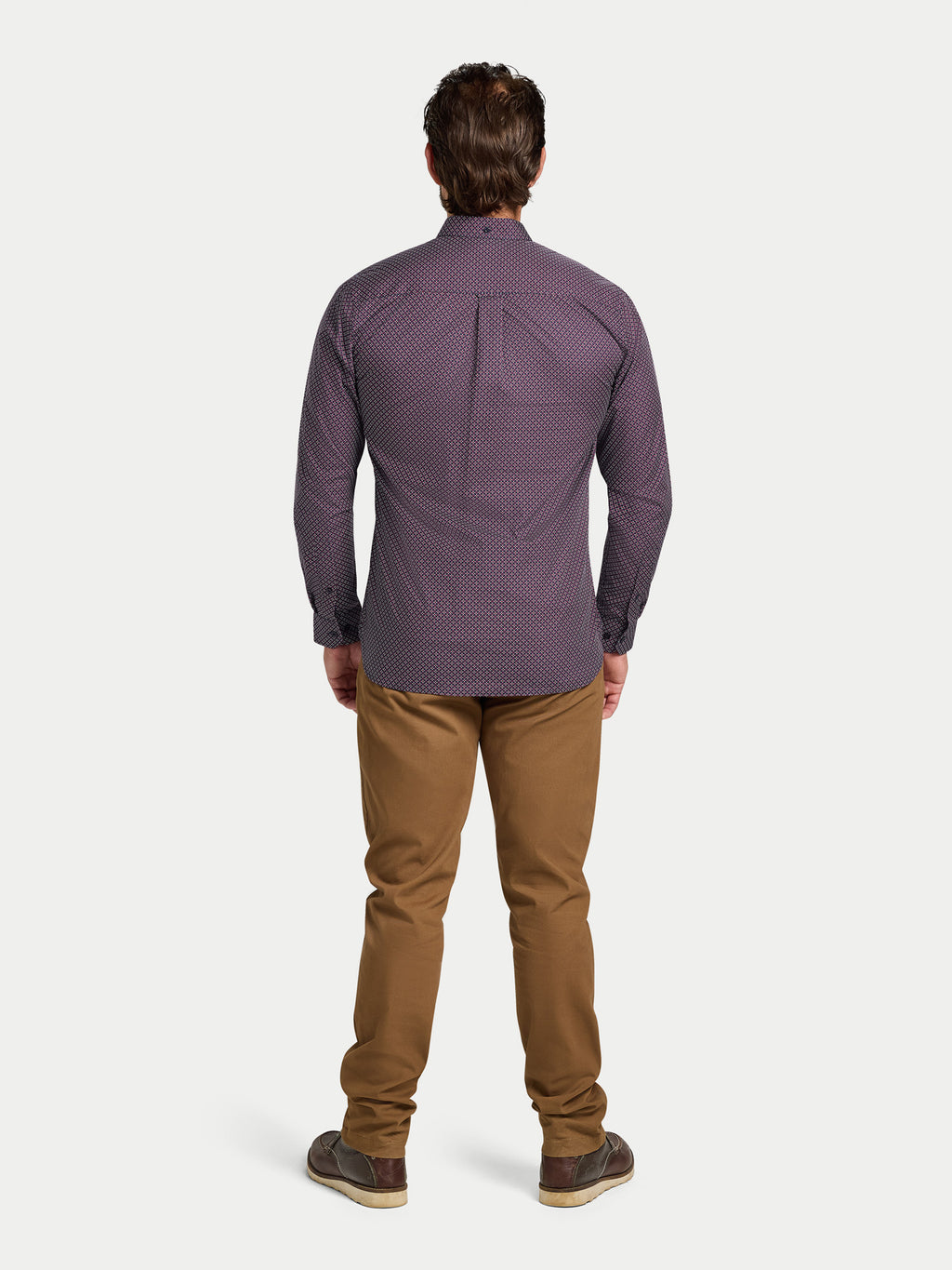 Man wearing a purple patterned shirt and brown pants on a white background