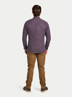 Man wearing a purple patterned shirt and brown pants on a white background