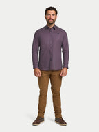 Man wearing a purple patterned shirt and brown pants on a white background