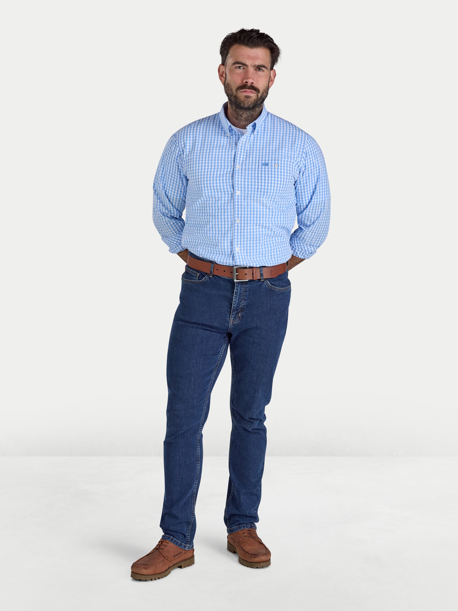 Man wearing a blue checkered shirt and jeans on a white background