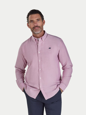 Man wearing a pink shirt with a small logo on a white background