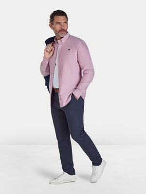 Man wearing a pink shirt, navy pants, and white sneakers on a white background