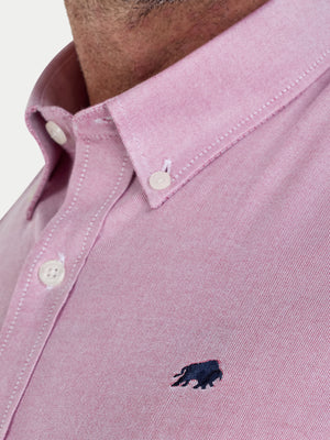 Close-up of a pink shirt with a small logo on the chest.