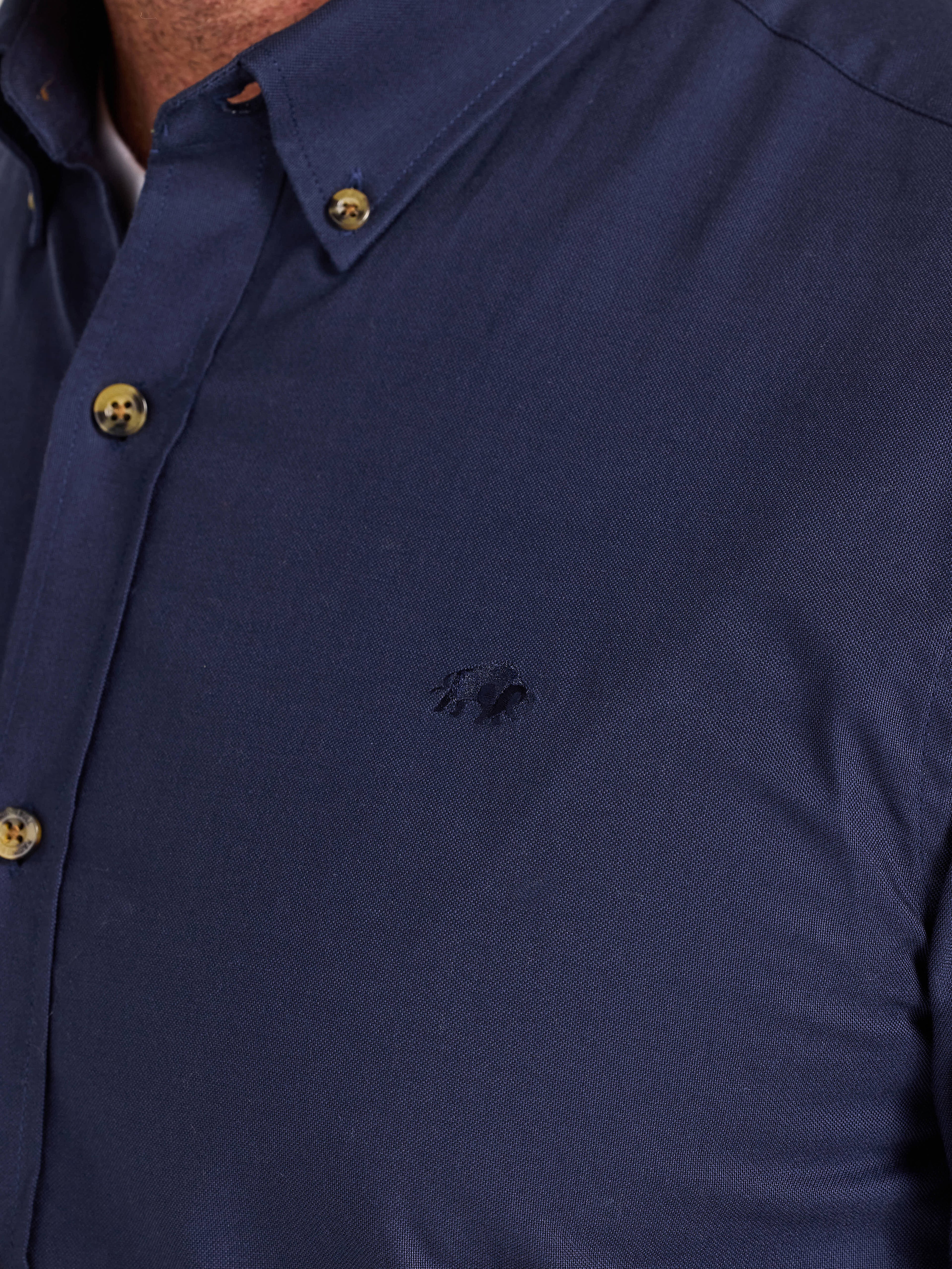 Navy blue shirt with gold buttons on a plain background