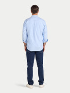 Man wearing a light blue shirt and dark blue jeans on a white background