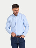 Man wearing a light blue button-up shirt and dark jeans on a white background