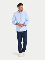 Man wearing a light blue shirt and dark blue jeans on a white background