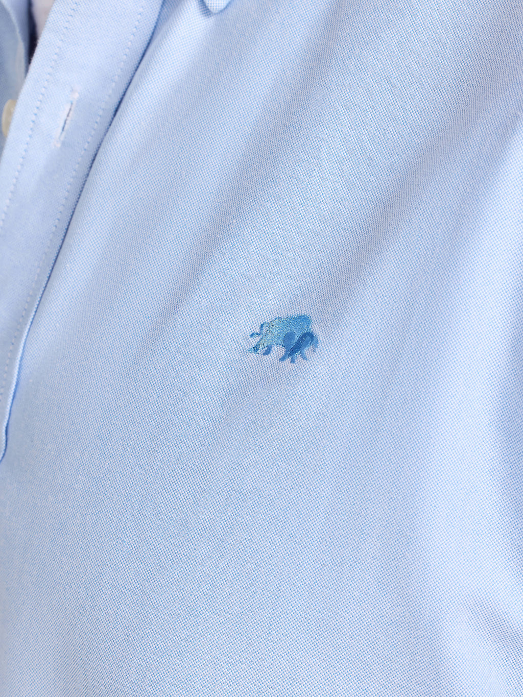 Close-up of a light blue polo shirt with a small logo on a white background