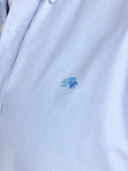 Close-up of a light blue polo shirt with a small logo on a white background