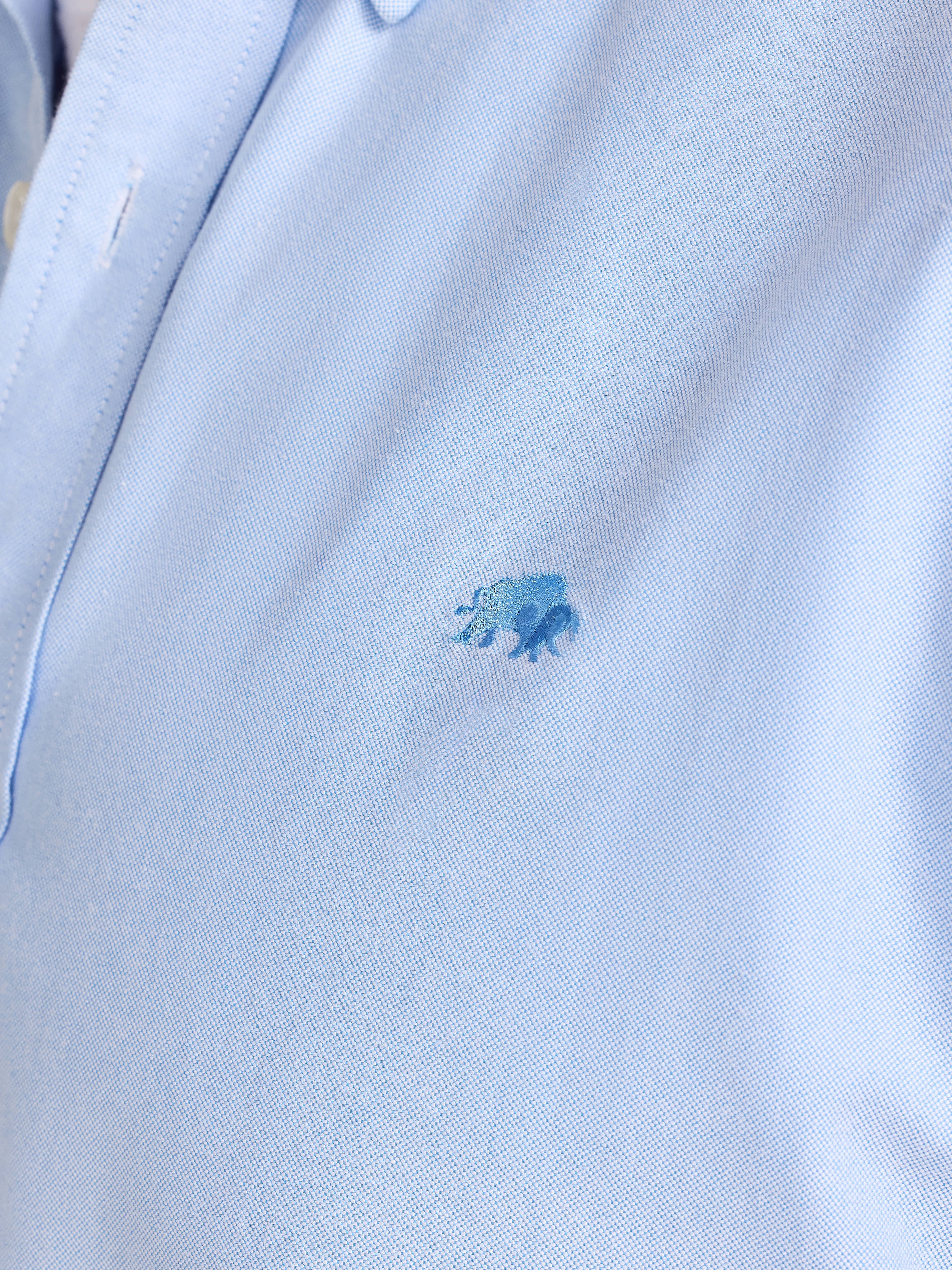 Close-up of a light blue polo shirt with a small logo on a white background