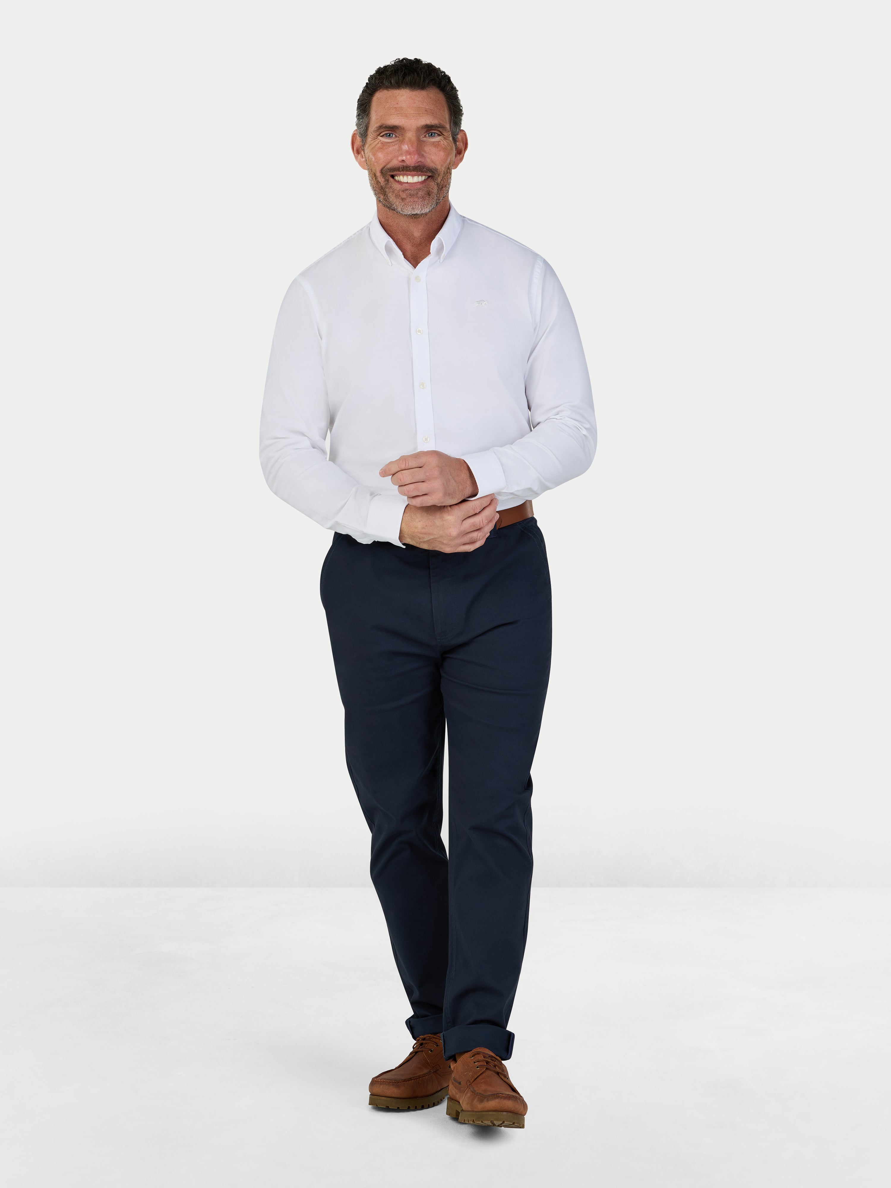 Man wearing a white dress shirt and navy pants on a white background