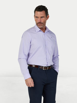 Man wearing a light purple striped dress shirt and dark blue pants on a white background