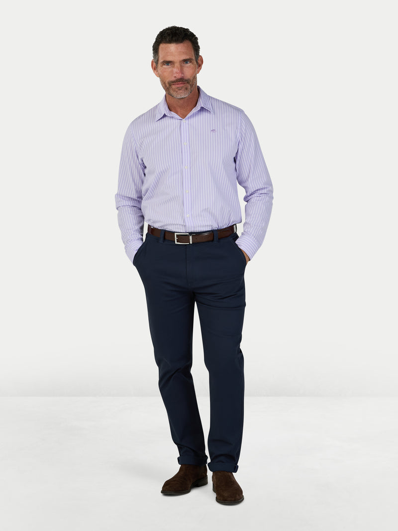 Man wearing a light purple striped shirt and navy pants on a white background