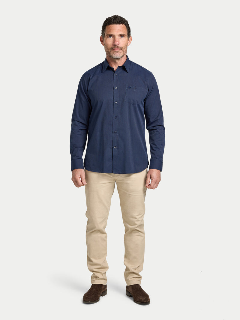 Man wearing a navy shirt and beige pants on a white background