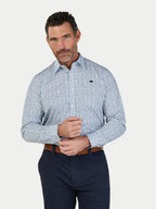 Man wearing a patterned shirt and dark pants on a light gray background