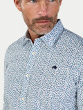 Man wearing a patterned shirt with a visible brand logo on a light background