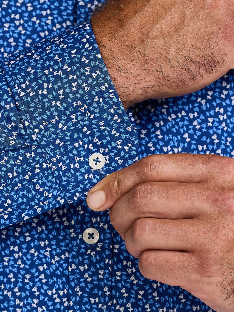 Close-up of a person adjusting a button on a blue patterned shirt.