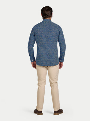 Man wearing a blue patterned shirt and beige pants on a white background