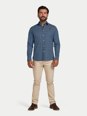 Man wearing a blue patterned shirt and beige pants on a white background