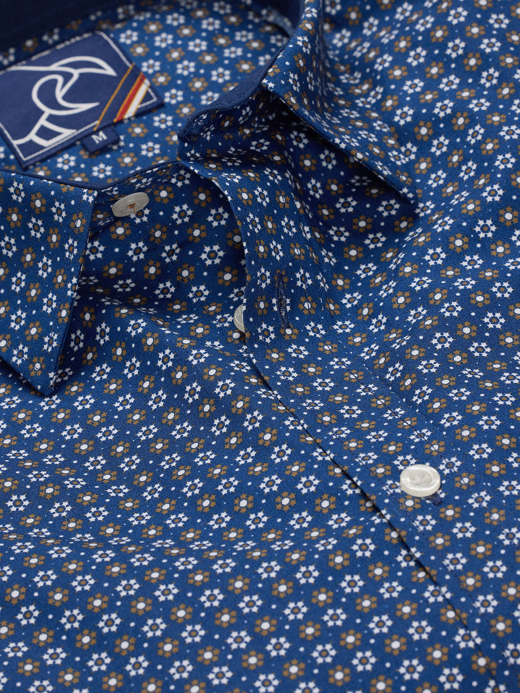 A navy-colored, long sleeve, button-up shirt with a geometric pattern, displayed in a folded state.