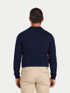 Man wearing a navy sweater and beige pants on a light gray background