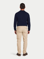 Man wearing a navy sweater and beige pants on a light gray background