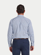 Man wearing a blue patterned shirt and navy pants on a light gray background