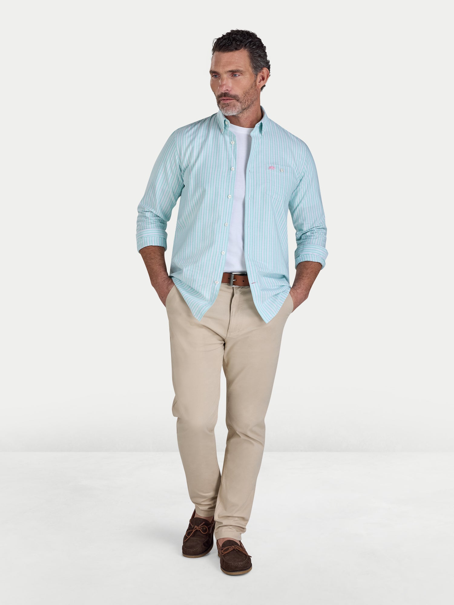 Man wearing a light blue checkered shirt and beige pants on a white background