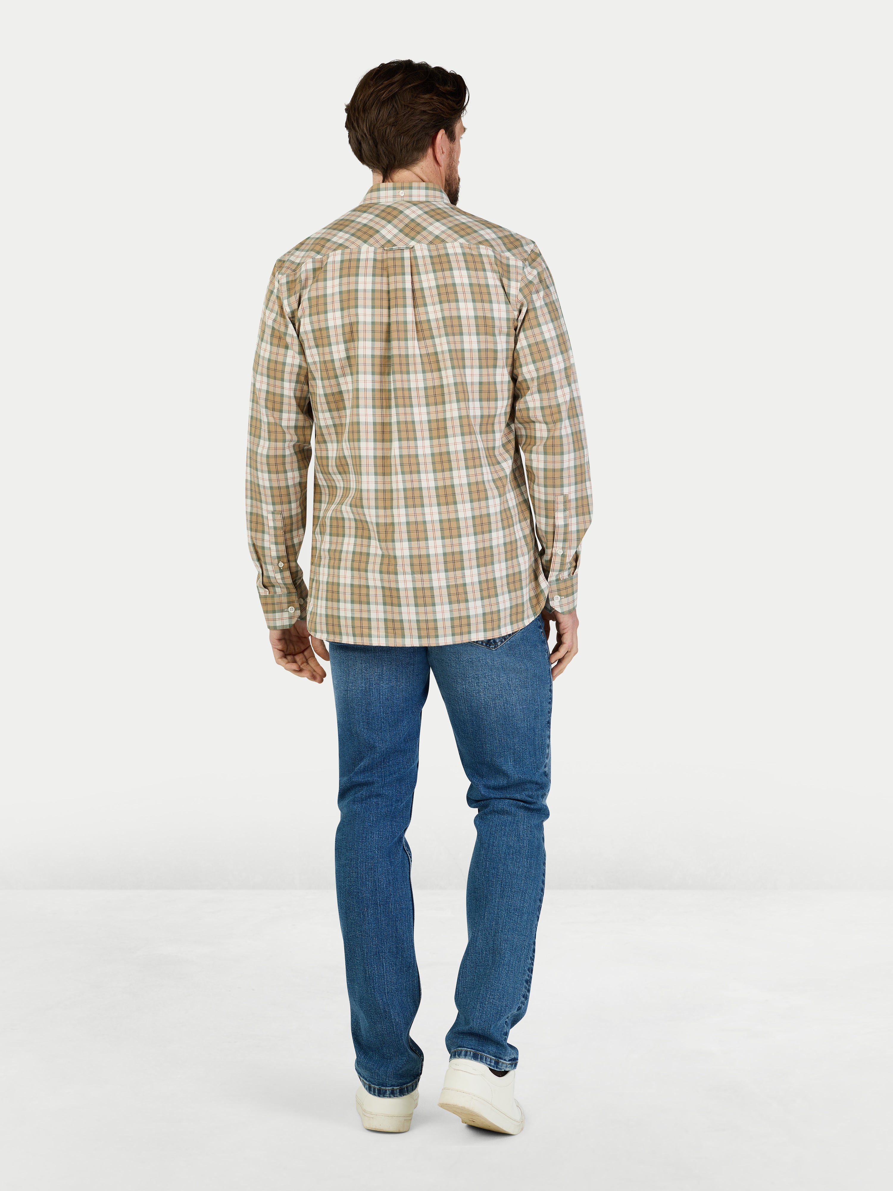 Man wearing a plaid shirt and blue jeans on a white background