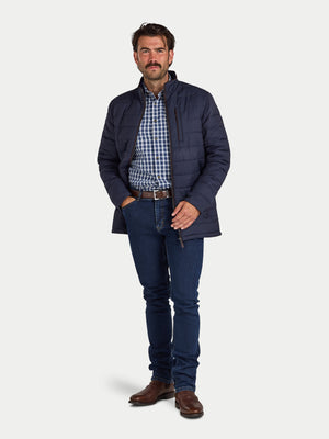 Man wearing a navy puffer jacket, checkered shirt, and jeans on a white background