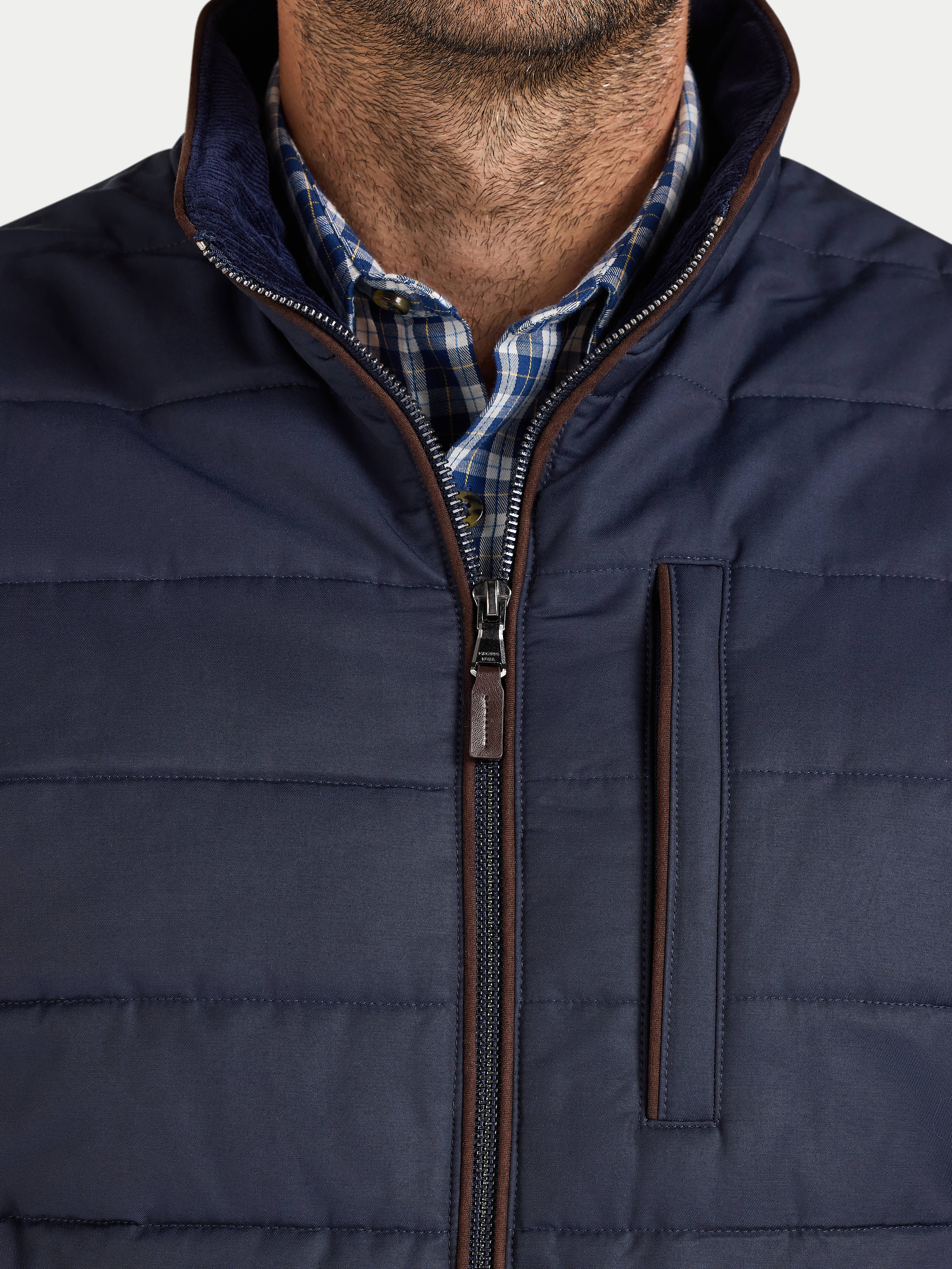 Navy puffer jacket with a plaid shirt underneath on a white background
