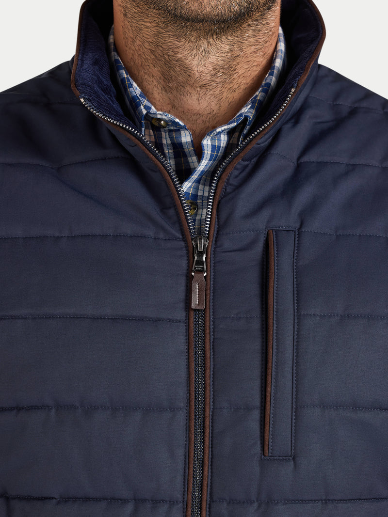 Navy puffer jacket with a plaid shirt underneath on a white background