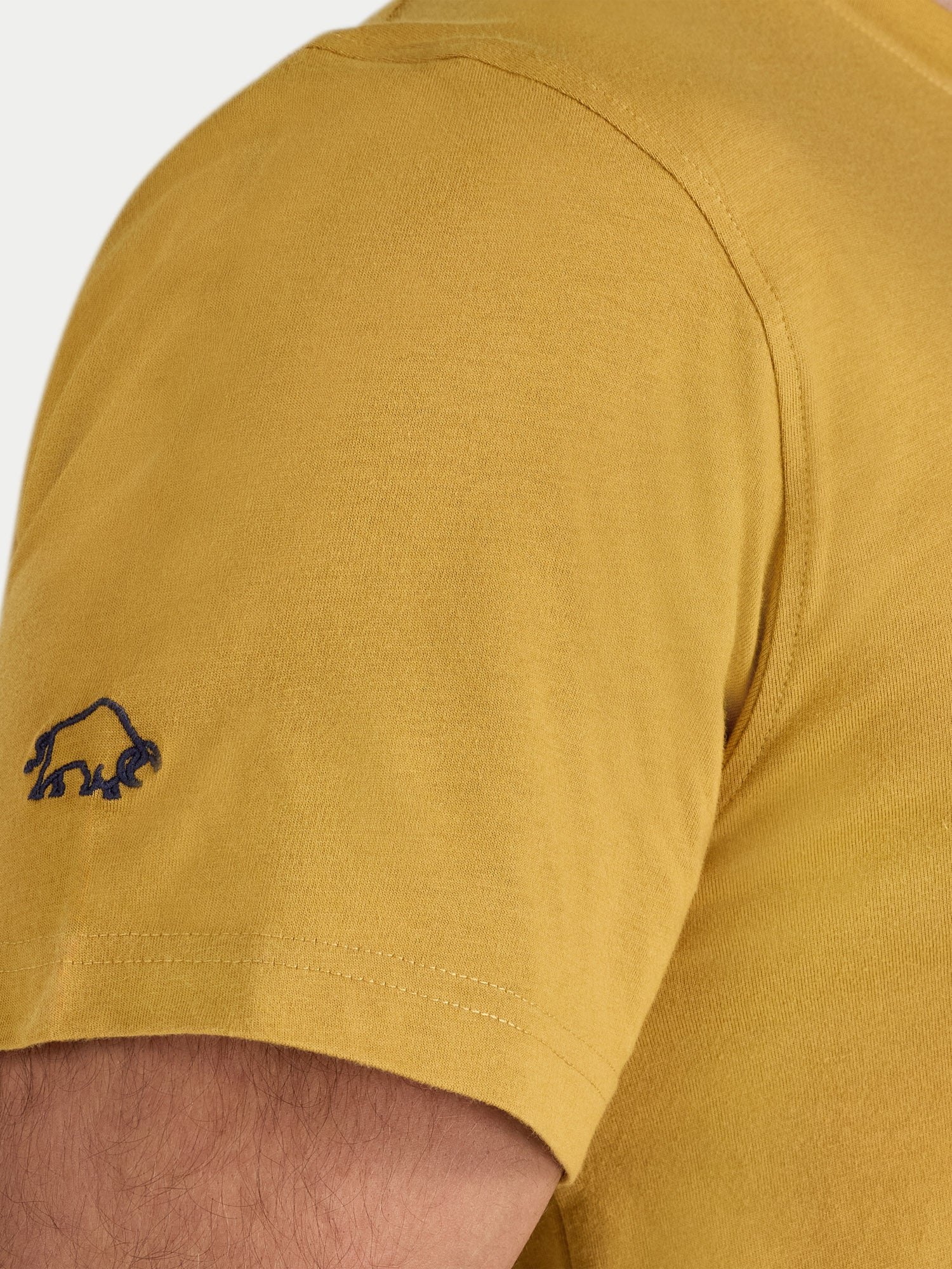 Close-up of a mustard yellow t-shirt with a small logo on the sleeve.