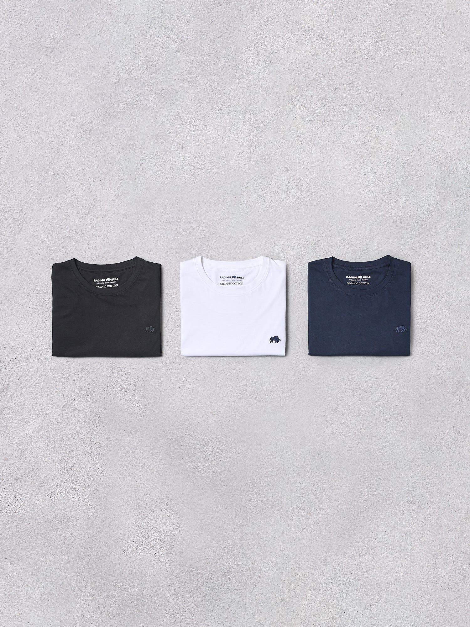 Three t-shirts in black, white, and navy on a gray background