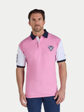Man wearing a pink polo shirt with white sleeves and navy accents on a light gray background