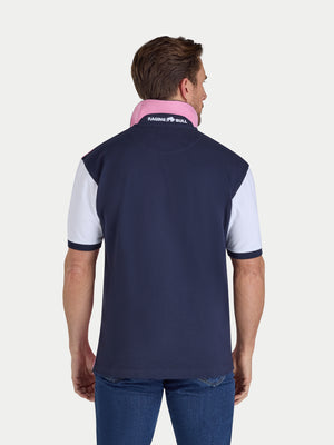 Man wearing a navy and white polo shirt with a visible brand logo on a light gray background