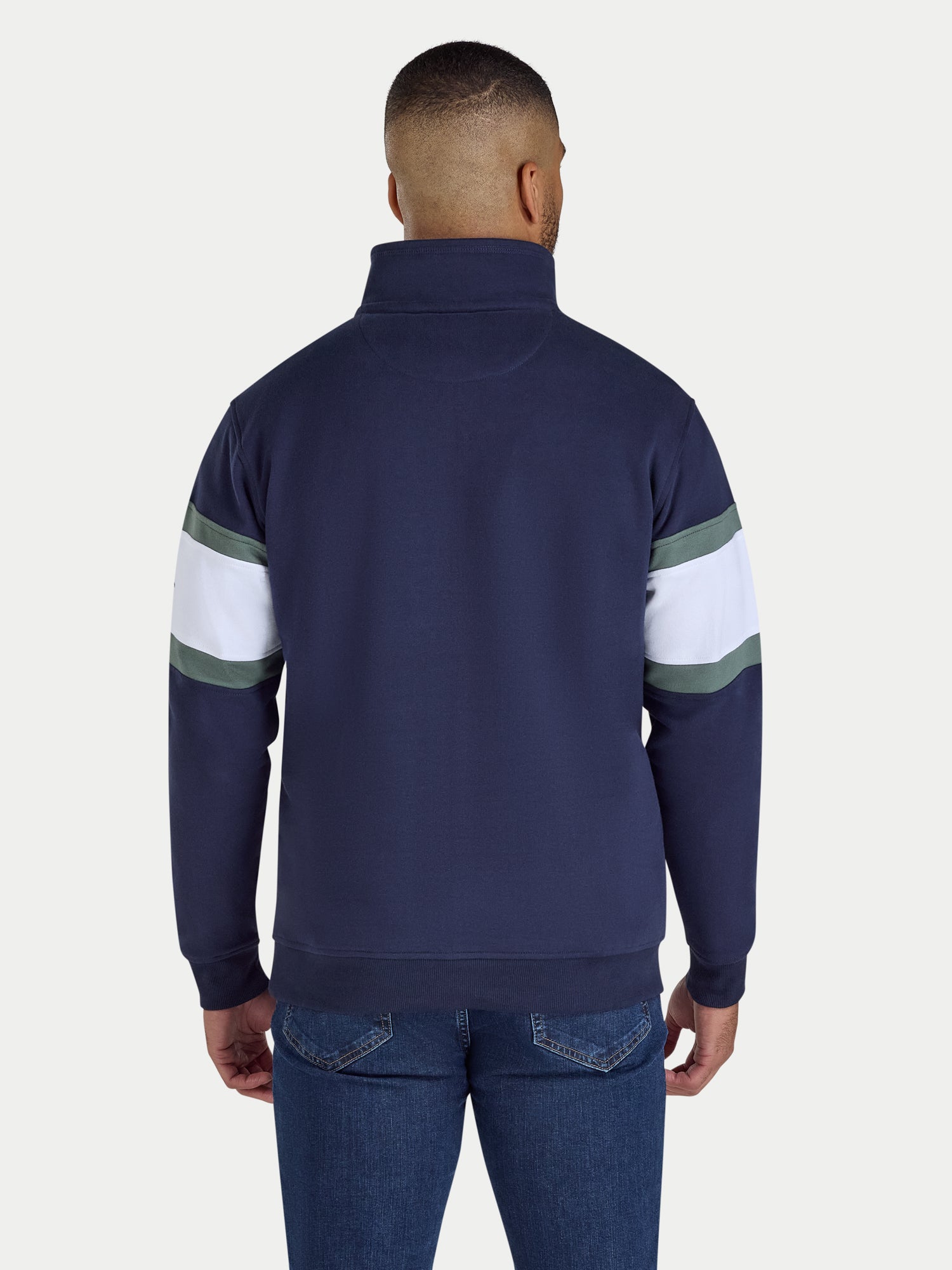 Person wearing a navy blue sweater with white and green stripes on sleeves against a white background