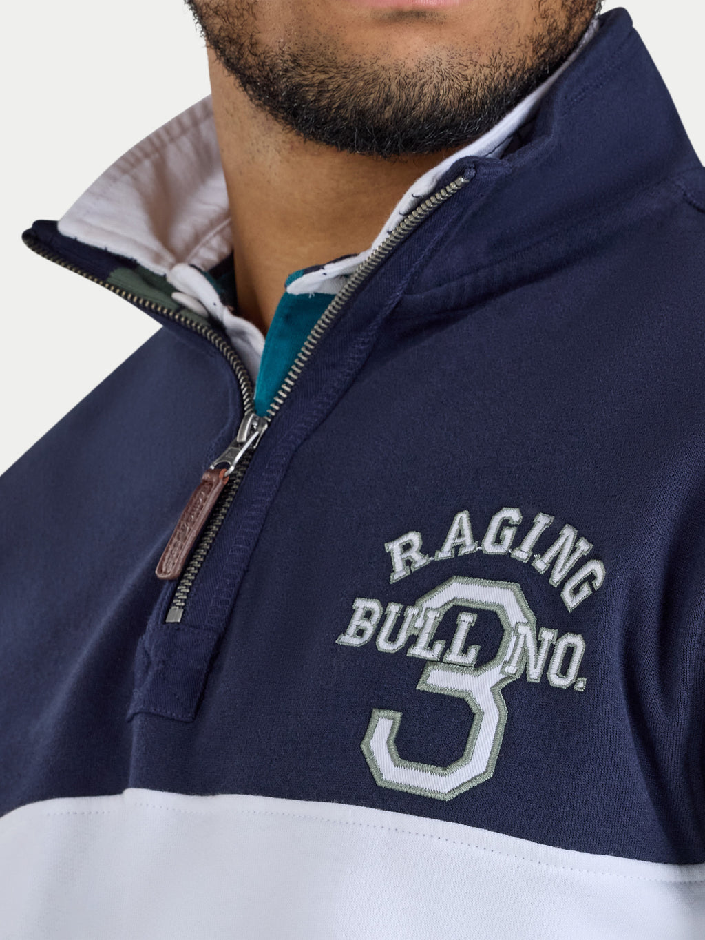 Navy and white jacket with 'Raging Bull' branding on a light gray background
