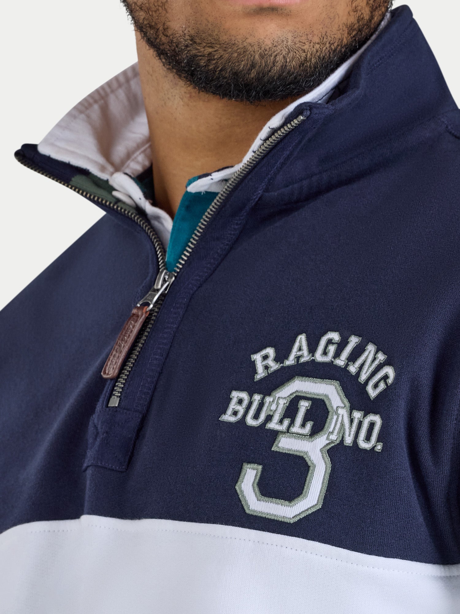Navy and white jacket with 'Raging Bull' branding on a light gray background