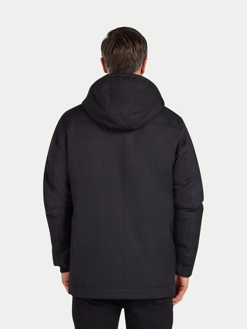Person wearing a black jacket with a hood on a white background