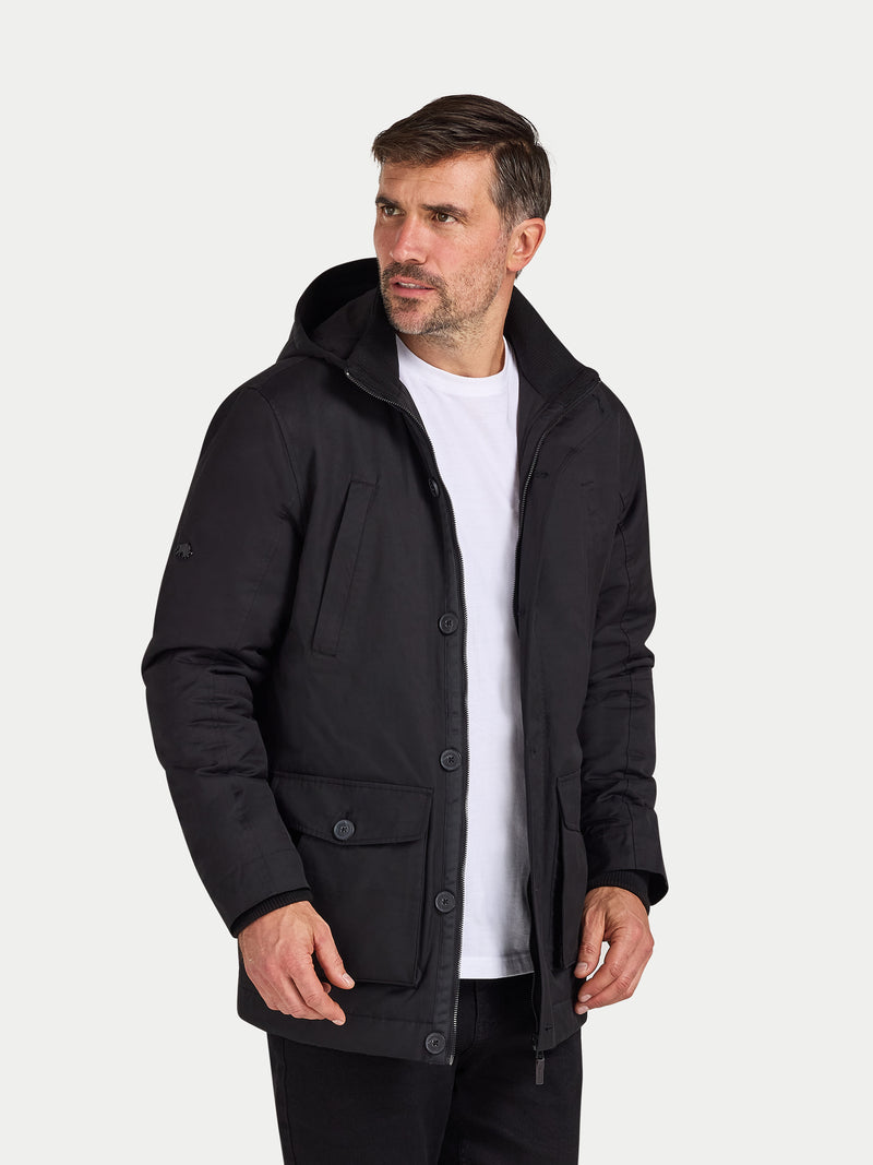 Man wearing a black jacket over a white shirt on a white background