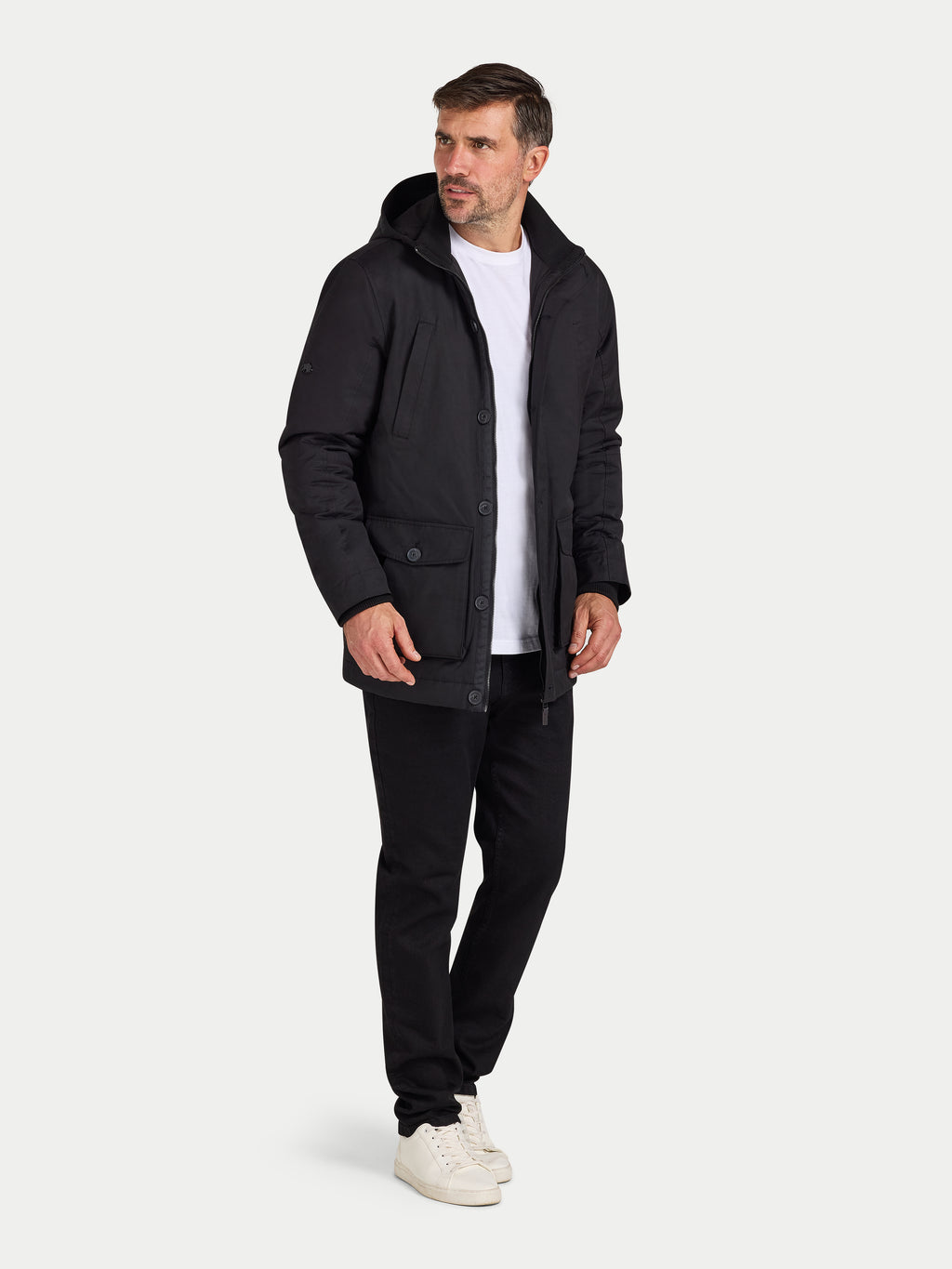 Man wearing a black coat, white shirt, and black pants on a white background