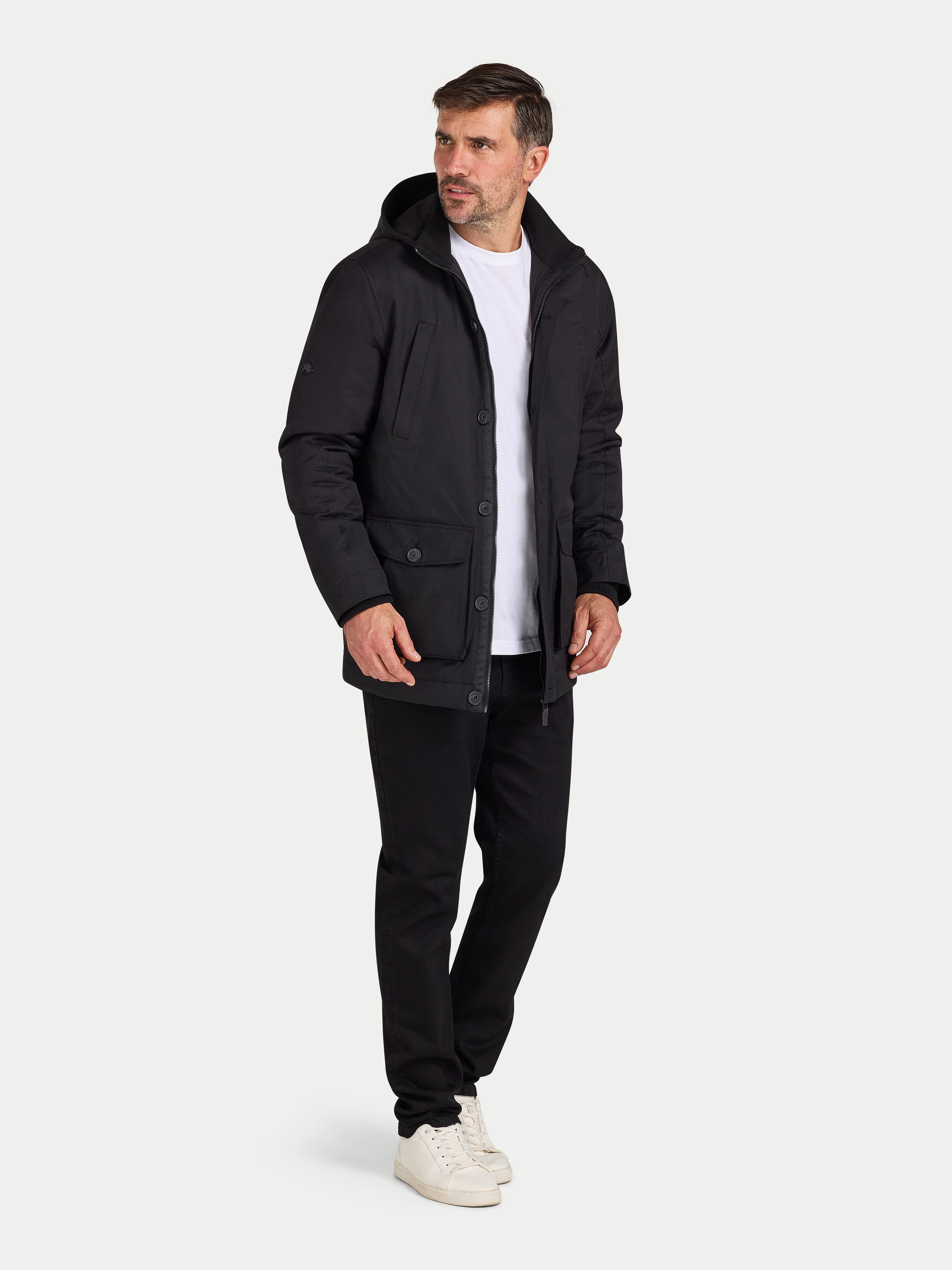 Man wearing a black coat, white shirt, and black pants on a white background