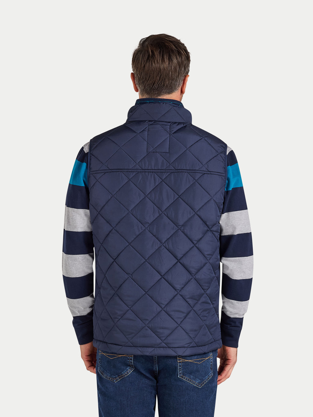 Person wearing a navy quilted jacket with striped sleeves on a white background