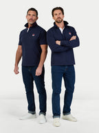 Two men wearing navy jackets and jeans standing against a white background