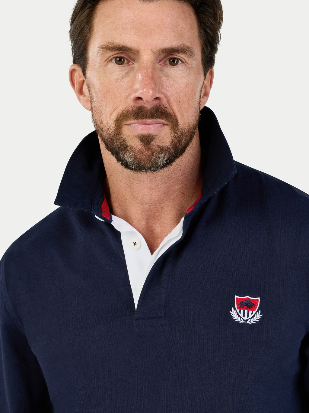 Man wearing a navy blue pullover with a logo on a white background
